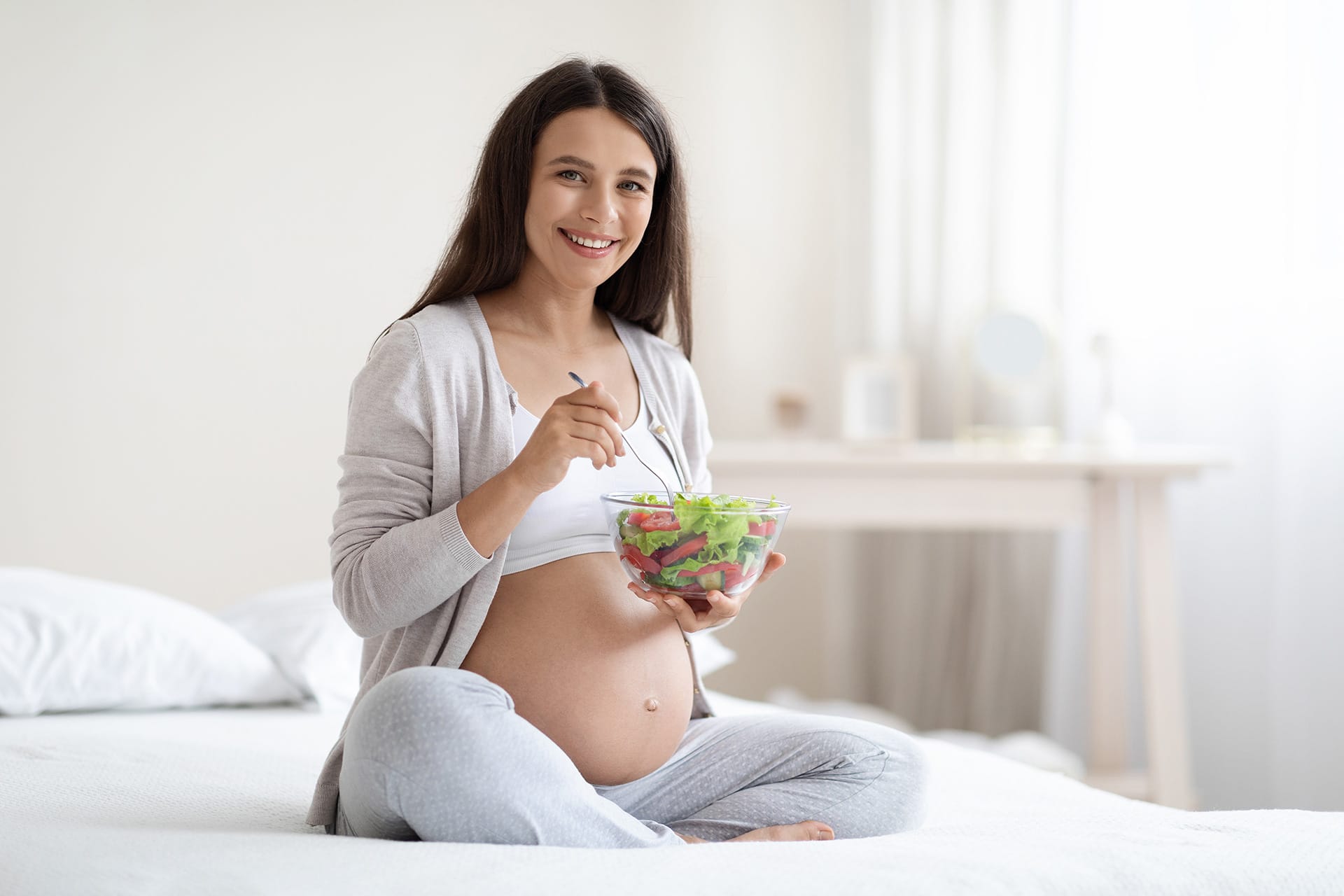 Attractive pregnant woman eating healthy meal at home